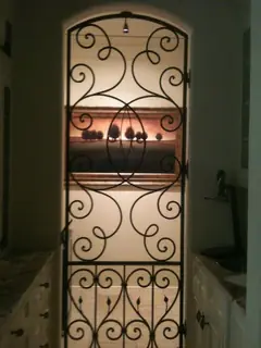 Ornamenterat galler framför hyllor.