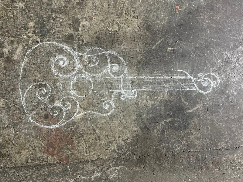 Gitarrkontur med spiraler, ritad med krita på verkstadsgolvet.